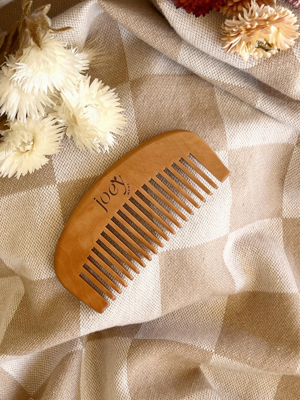 Wooden comb on a textured fabric background with flowers